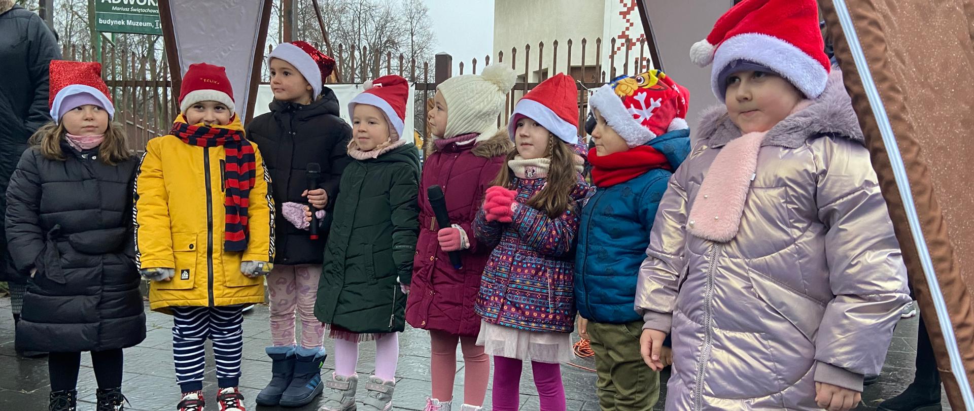 Dzieci uczestniczące w Jarmarku stoją przy prowadzących wydarzenie