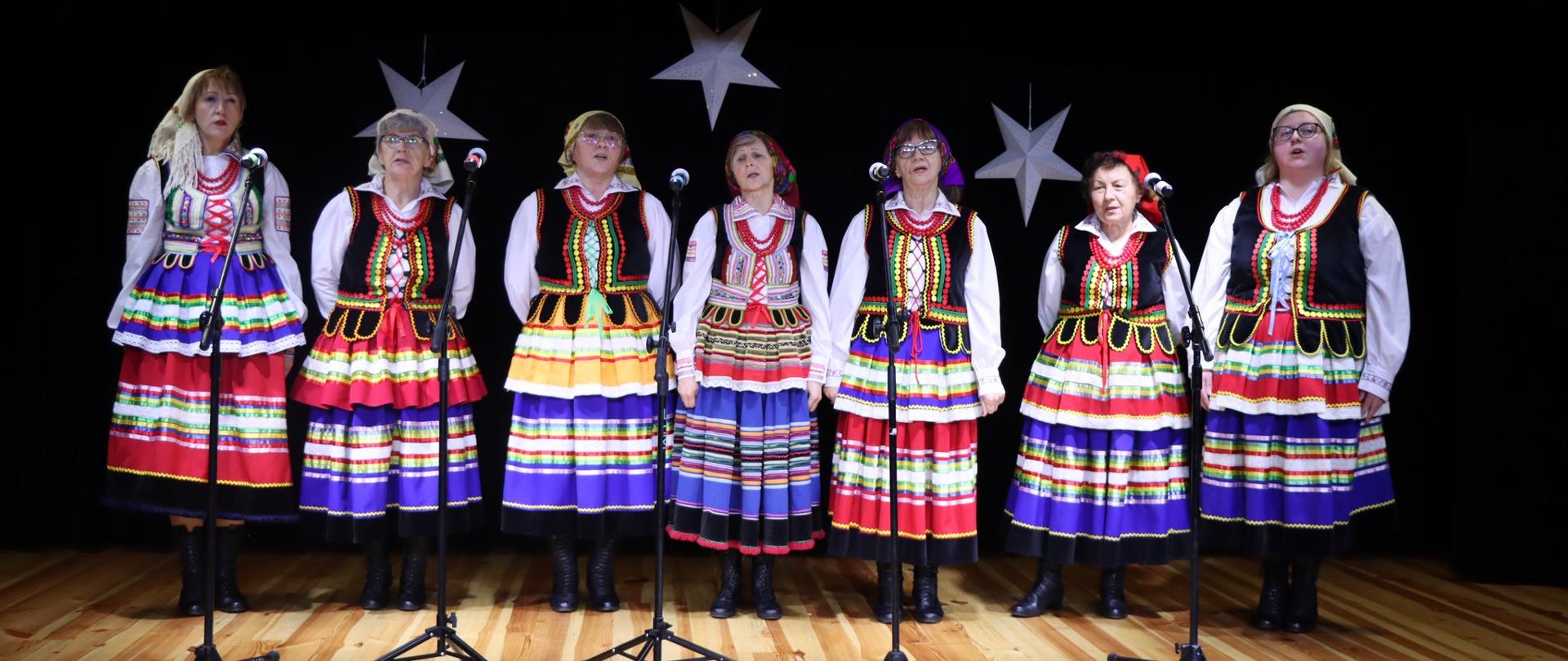 Na zdjęciu kobiecy zespół podczas występu na scenie. Panie ubrane są w kolorowe stroje ludowe.