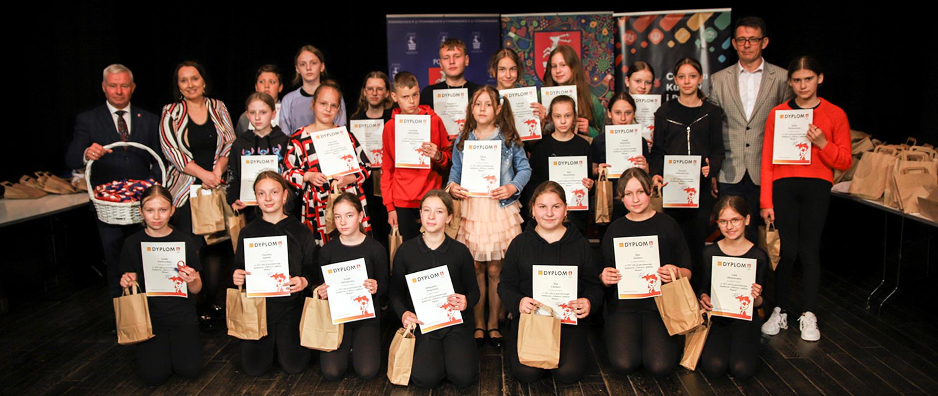 Na zdjęciu członkowie koła teatralnego, którzy trzymają otrzymane dyplomy i nagrody, pozują do zdjęcia ze Starostą Kraśnickim oraz Przewodniczącym Rady Powiatu w Kraśniku. 