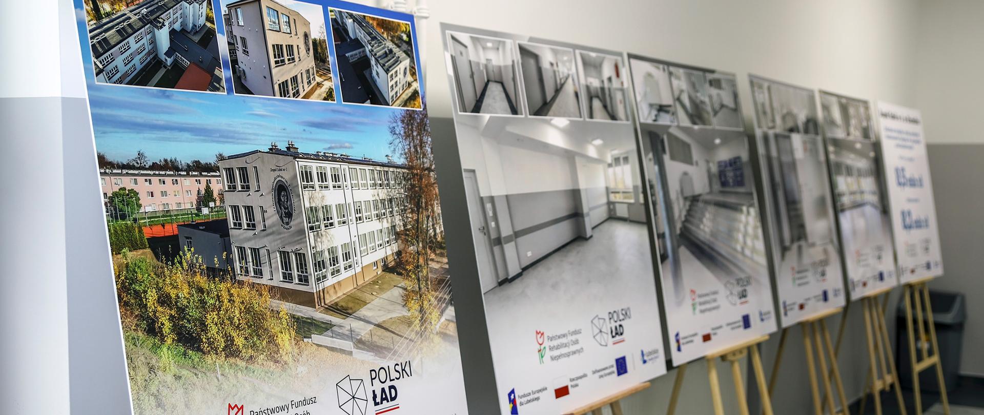 Zdjęcie przedstawia ekspozycję w pomieszczeniu, na której na drewnianych sztalugach ustawiono sześć dużych plansz informacyjnych dotyczących inwestycji i dofinansowania. Najbliżej widoczna plansza, po lewej, ukazuje dużą fotografię fasady budynku Zespołu Szkół nr 1 w Kraśniku oraz trzy mniejsze zdjęcia prezentujące jego nowoczesną rozbudowę. Na dole planszy widoczne są logotypy i napisy informujące o źródłach finansowania, w tym POLSKI ŁAD i Państwowy Fundusz Rehabilitacji Osób Niepełnosprawnych oraz logotypy funduszy europejskich i Województwa Lubelskiego. Pozostałe plansze, w głębi, po prawej, ustawione pod kątem, prezentują głównie wizualizacje wnętrza modernizowanej placówki. Na ostatniej planszy widnieją kwoty dofinansowania. Wszystkie plansze mają podobny układ graficzny z informacjami o dofinansowaniu.