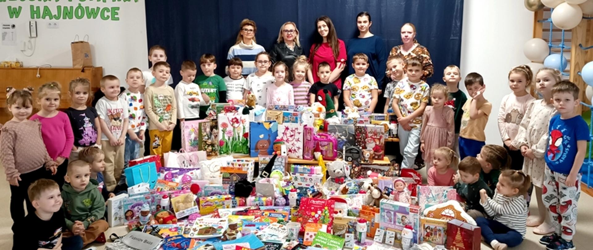 Społeczność przedszkolna pozuje z zebranymi rzeczami
