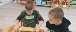 Wspólne pieczenie pierniczków - dzieci siedzą przy stole i wykonują czynności związane z przygotowaniem ciasteczek. Pozują przy tym do zdjęć