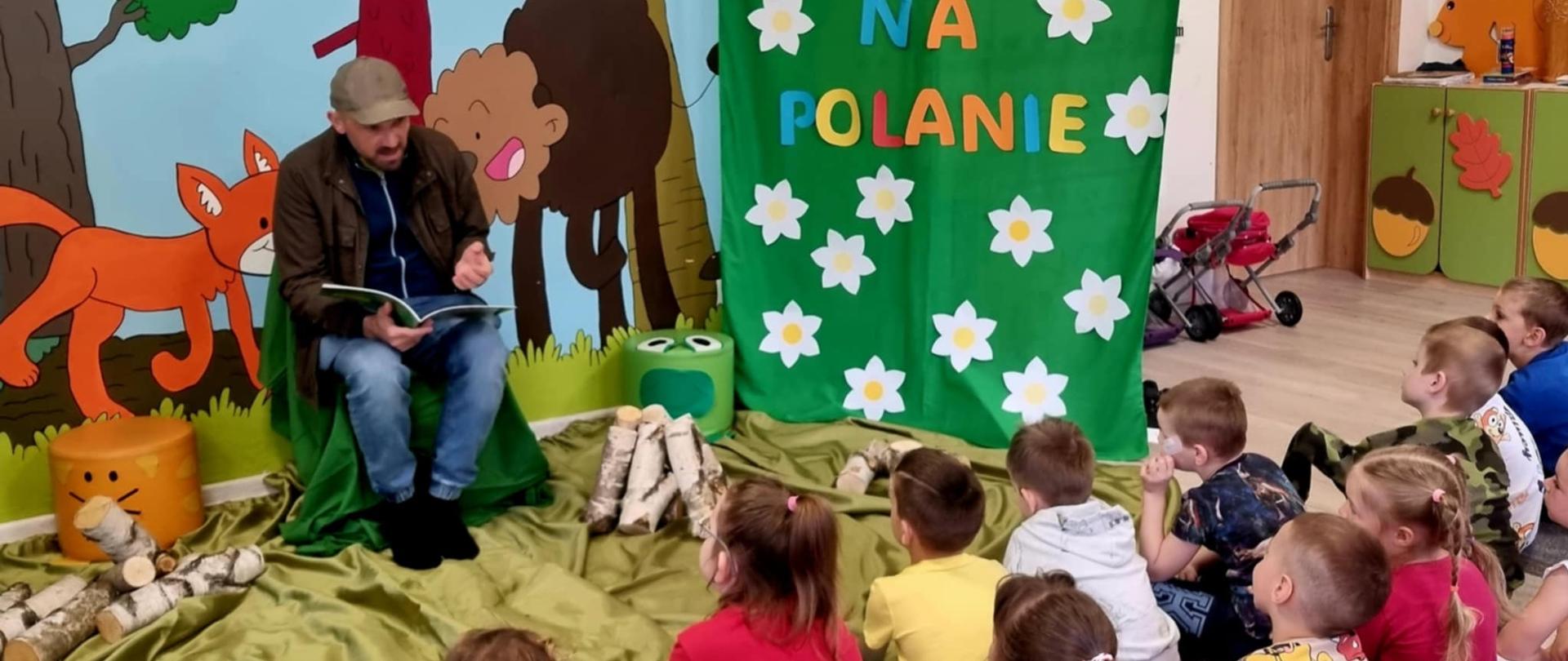 Akcja "Czytanie na Polanie" - w przedszkolu, w scenerii stylizowanej na leśną polanę , dzieciom czyta Tomasz Samojlik - autor serii przygód Żubra Pompika.