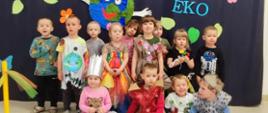 Dzieci pozują do zdjęcia na tle ścianki Pokaz EKO Mody