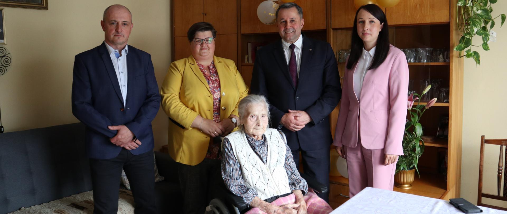 Zdjęcie przedstawia jubilatkę panią Zofie Żądło oraz Wójta Gminy, Kierownika USC, Sołtys Wsi i Grzegorza Żądło pozujących do zdjęcia