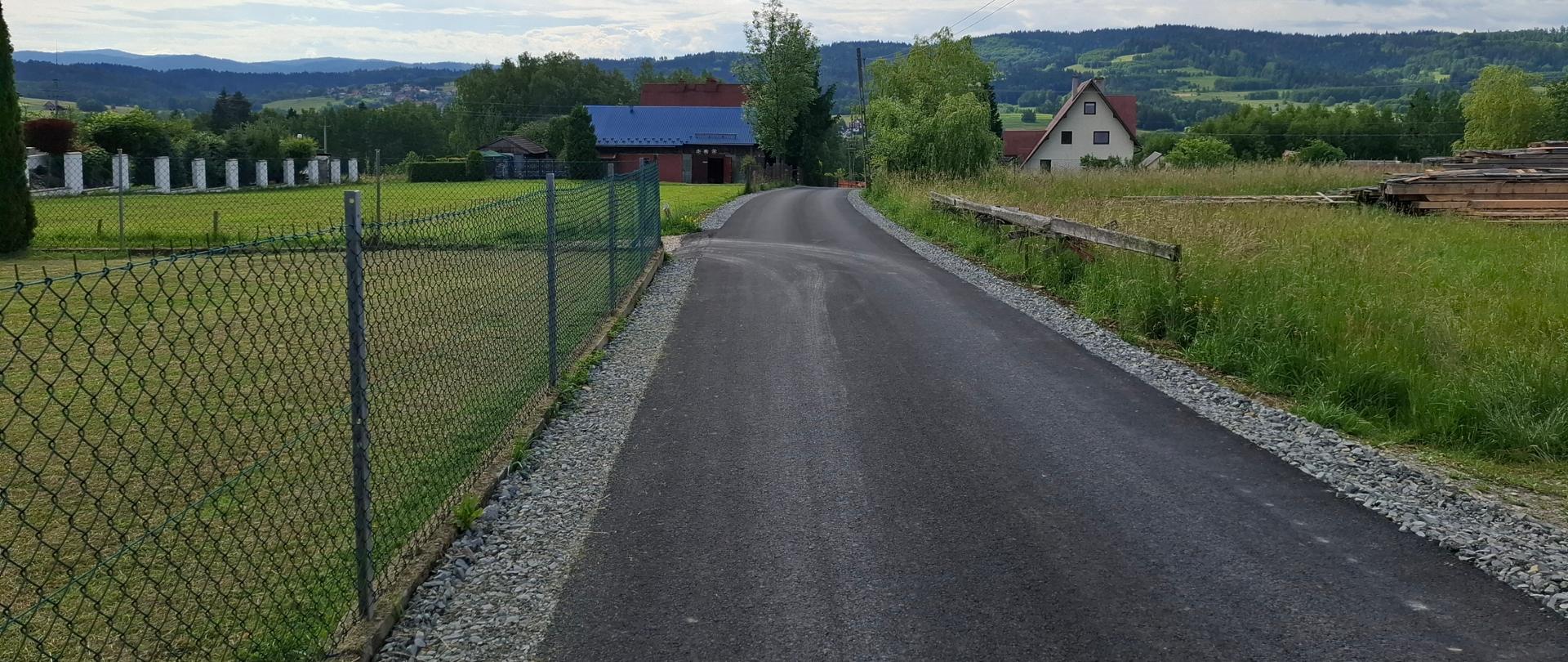 Zdjęcie przedstawia przebudowę drogi gminnej poprzez podbudowę dolnej i górnej nawierzchni asfaltowej na roli Winiarskówka w miejscowości Rokiciny Podhalańskie.