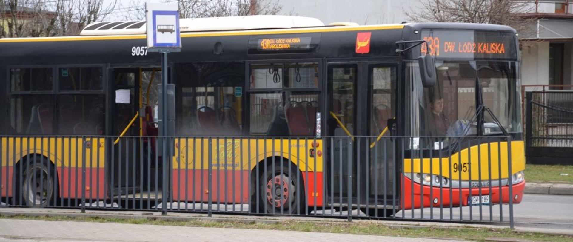 Zdjęcie przedstawia żółto-czerwony autobus linii 43A do Dw. Łódź Kaliska. Stoi on na krańcówce w Konstantynowie Łódzkim. Przed nim są grafitowe barierki oraz znak autobusu. 