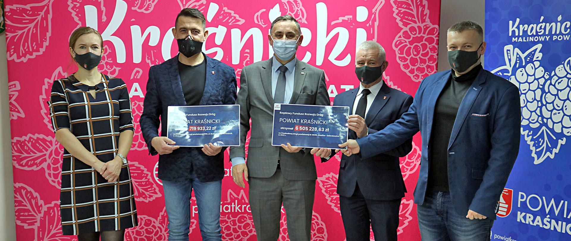 Na zdjęciu od lewej: Dyrektor Zarządu Dróg Powiatowych w Kraśniku Marta Gajewska, Przewodniczący Rady Powiatu w Kraśniku Jacek Dubiel, Poseł na Sejm Rzeczpospolitej Polskiej Kazimierz Choma, Starosta Kraśnicki Andrzej Rolla, Zastępca Dyrektora Zarządu Dróg Powiatowych w Kraśniku Michał Kondracki odebrali symboliczne promesy na realizację dwóch zadań z Rządowego Funduszu Rozwoju Dróg na realizację zadań inwestycyjnych: przebudowy drogi powiatowej nr 2701L ul. Budzyńska w Kraśniku oraz przebudowy drogi powiatowej nr 2639L relacji Józefów — Dzierzkowice. W tle znajduje się ściana promocyjna z napisem Malinowy Powiat w kolorze czerwonym. Po prawej stronie widać roll-up w kolorze niebieskim z hasłem promocyjnym Malinowy Powiat. Symboliczne czeki trzyma Przewodniczący Rady Powiatu Jacek Dubiel, Poseł na Sejm Rzeczpospolitej Polskiej Kazimierz Choma, Starosta Kraśnicki Andrzej Rolla oraz Zastępca Dyrektora Zarządu Drug Powiatowych w Kraśniku Michał Kondracki. 
