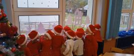 Dzieci wyglądają za okno, wypatrują odchodzącego Mikołaja