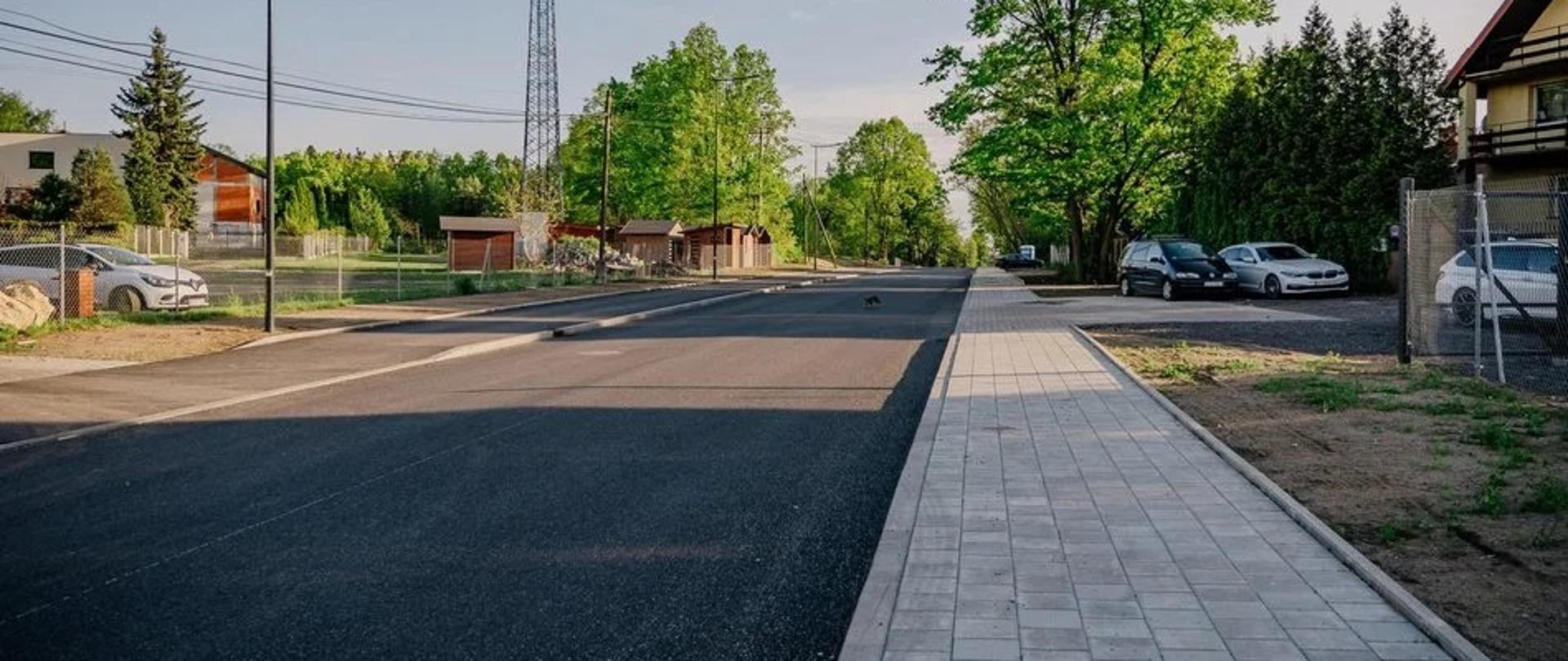 Wyremontowana ul. Szczecińska z nową nawierzchnią, chodnikiem i oświetleniem. W tle widoczna zabudowa jednorodzinna oraz maszt telekomunikacyjny.