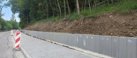 Palisada zabezpieczająca chodnik . W tle drzewa i droga.