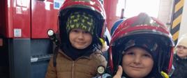 Dzieci pozują do zdjęcia w kasku strażackim