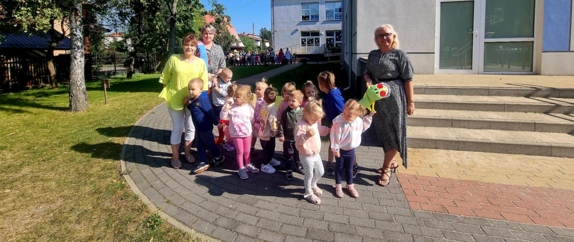 Pani Dyrektor, Nauczycielki i dzieci pozują do zdjęcia przed budynkiem przedszkola