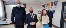 Na zdjęciu po lewej stronie: mł.insp. Jacek Figel, Starosta Kraśnicki Andrzej Rolla oraz laureatka konkursu, która trzyma dyplom oraz niebieską torbę z nagrodami. 
