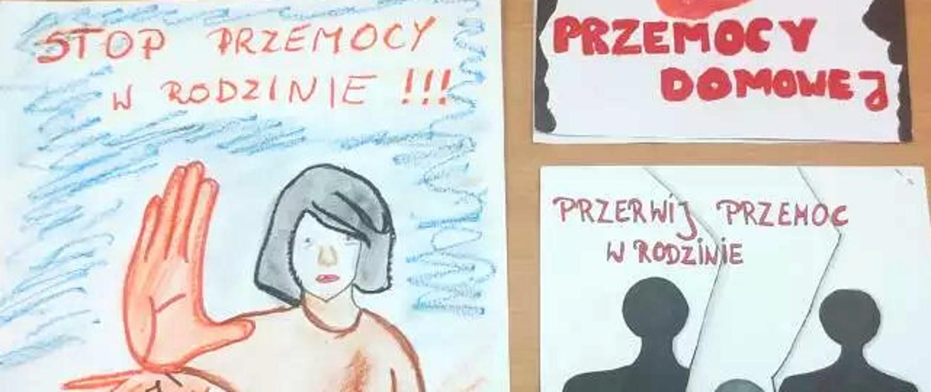 Na drewnianym blacie stołu 3 plakaty konkursowe o tematyce przemocy w rodzinie