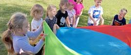 Zabawy na powietrzu - dzieci trzymają kolorową płachtę
