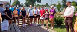 Uczestnicy turnieju stojący na tle kortu tenisowego. Pierwszy od lewej stoi Zastępca Dyrektora Miejskiego Ośrodka Sportu i Rekreacji w Kraśniku Łukasz Bielak