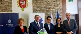 Pięć stojących osób ubranych galowo, od lewej kolejno: kobieta, mężczyzna, dwie kobiety i mężczyzna, w tle roll-upy