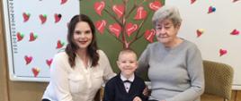 Chłopczyk pozuje do zdjęcia ze swoją babcią i mamą