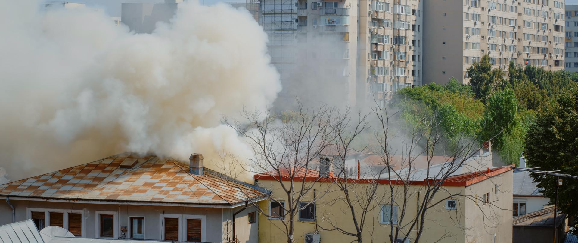 Flames going out from burning house in neighbourhood. Smoke emerging from roof on fire in city landscape. Dangerous fumes and smog from explosion getting out of destroyed building