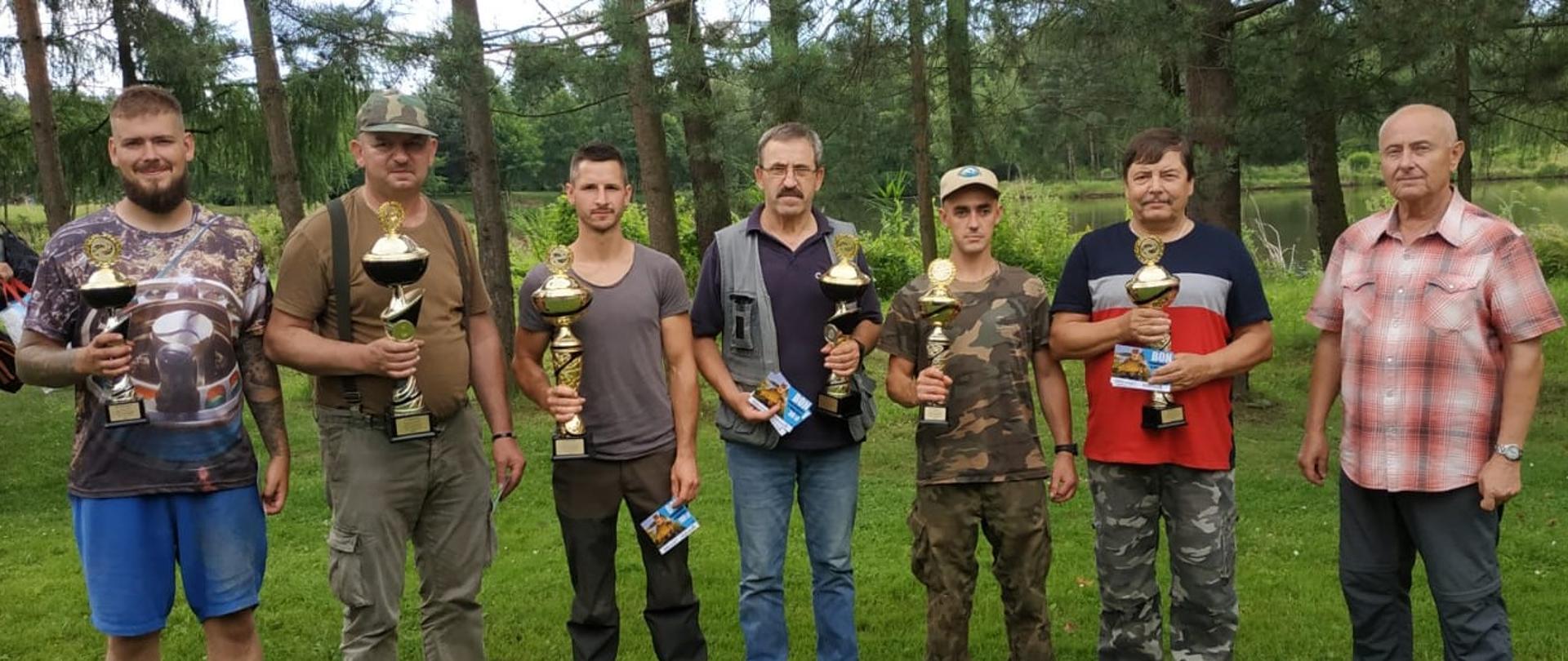 Finaliści zawodów o Puchar Wójta Gminy Hażlach. Stoją z pucharami na trawie na tle drzew.