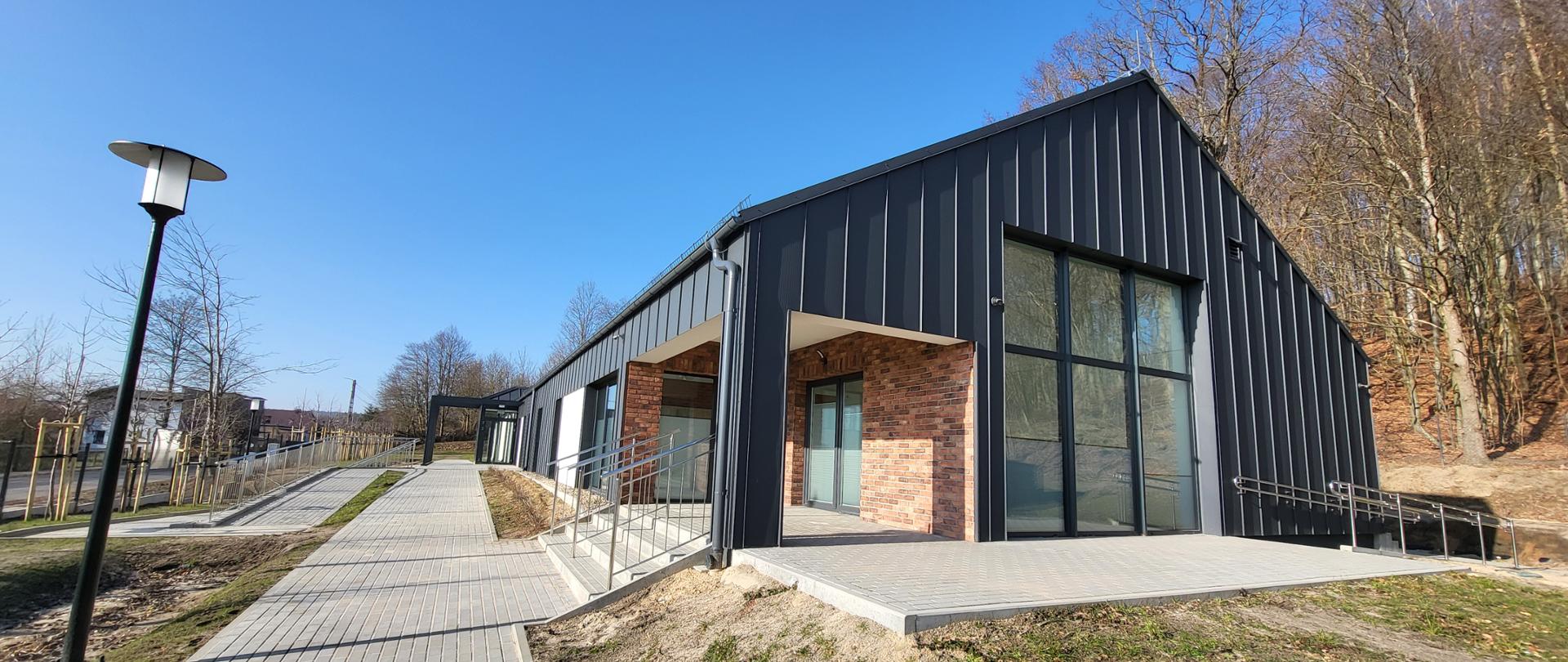 Budynek z tarasem z kostki brukowej przy chodziku na tle drzew i nieba