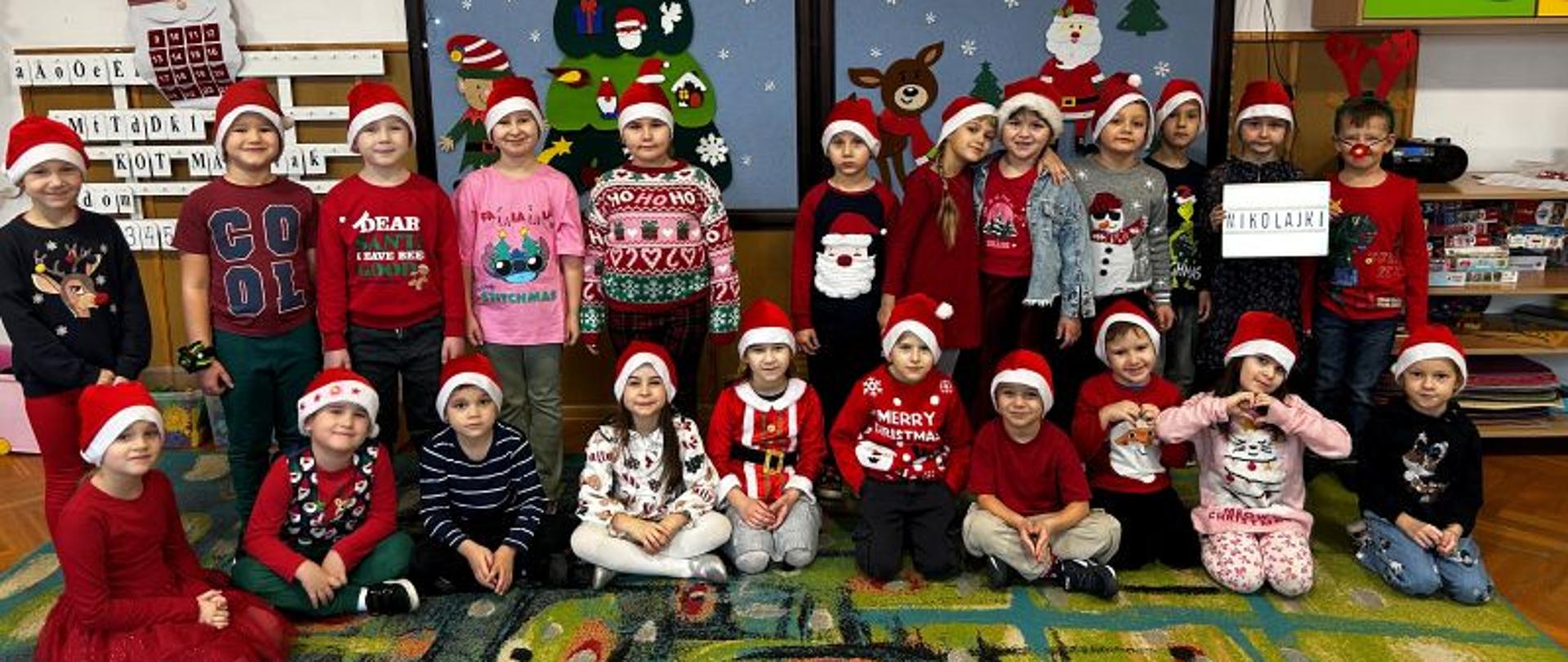 Dzieci z czapkach św. Mikołaja pozują do wspólnego zdjęcia