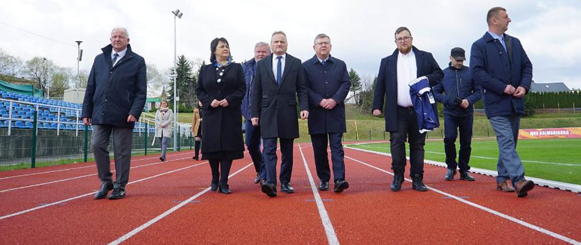 Wizyta Marszałka Województwa Małopolskiego Witolda Kozłowskiego na stadionie Kalwarianki. Grupa osób spacerująca po bieżni sportowej. 