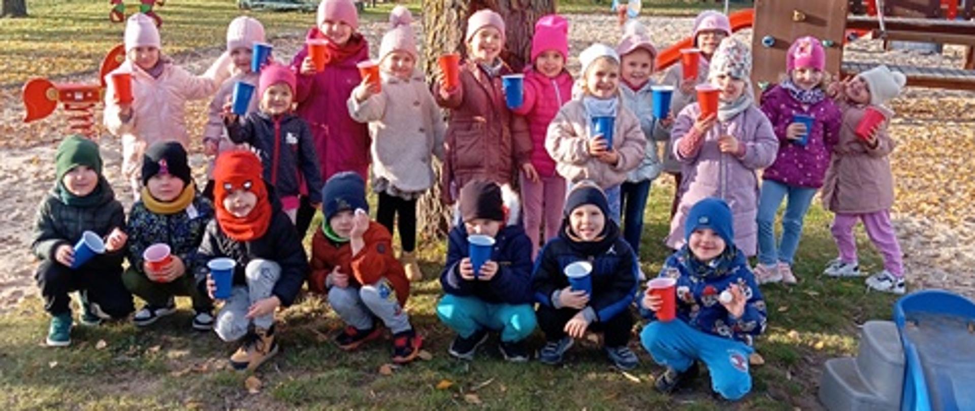 Na placu zabaw - dzieci pozują do zdjęcia przy drzewie