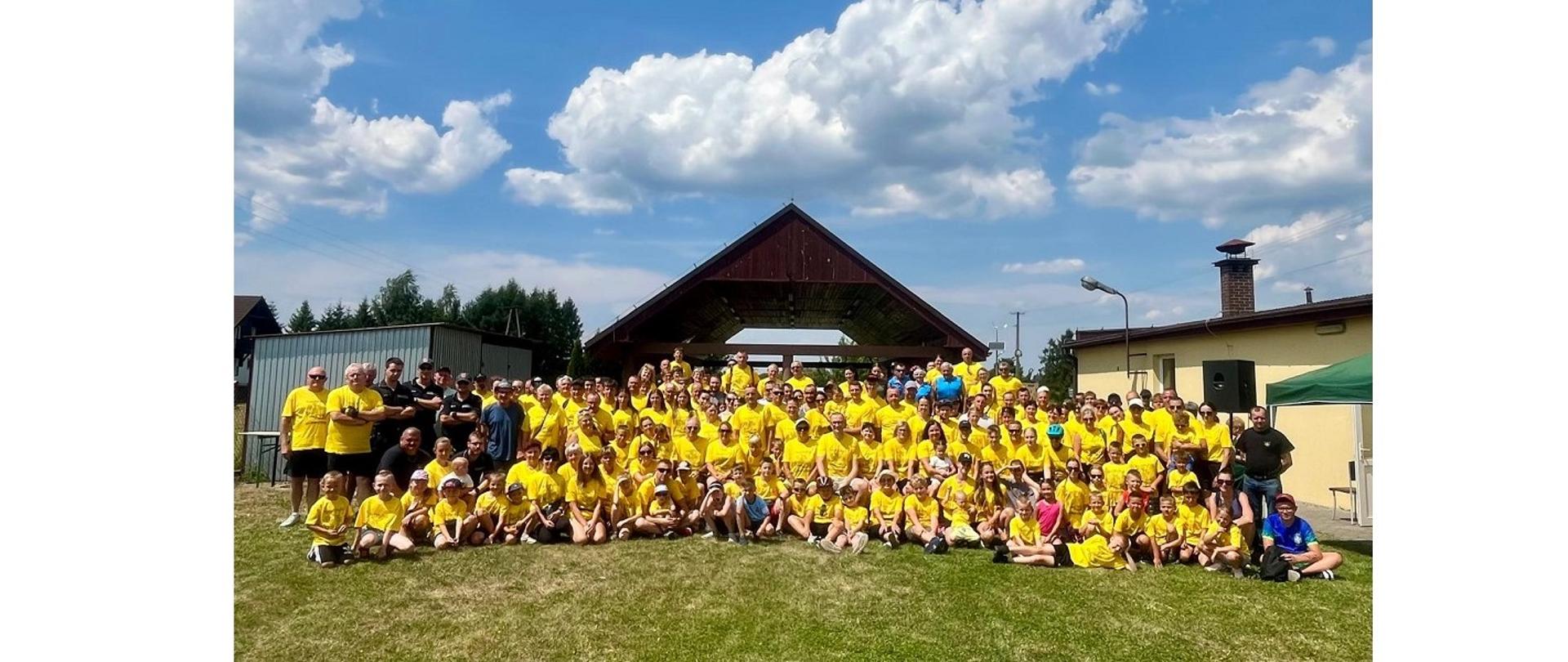Wspólna fotografia wszystkich uczestników rajdu. Większość pozujących do zdjęcia osób jest ubrana w charakterystyczne żółte koszulki