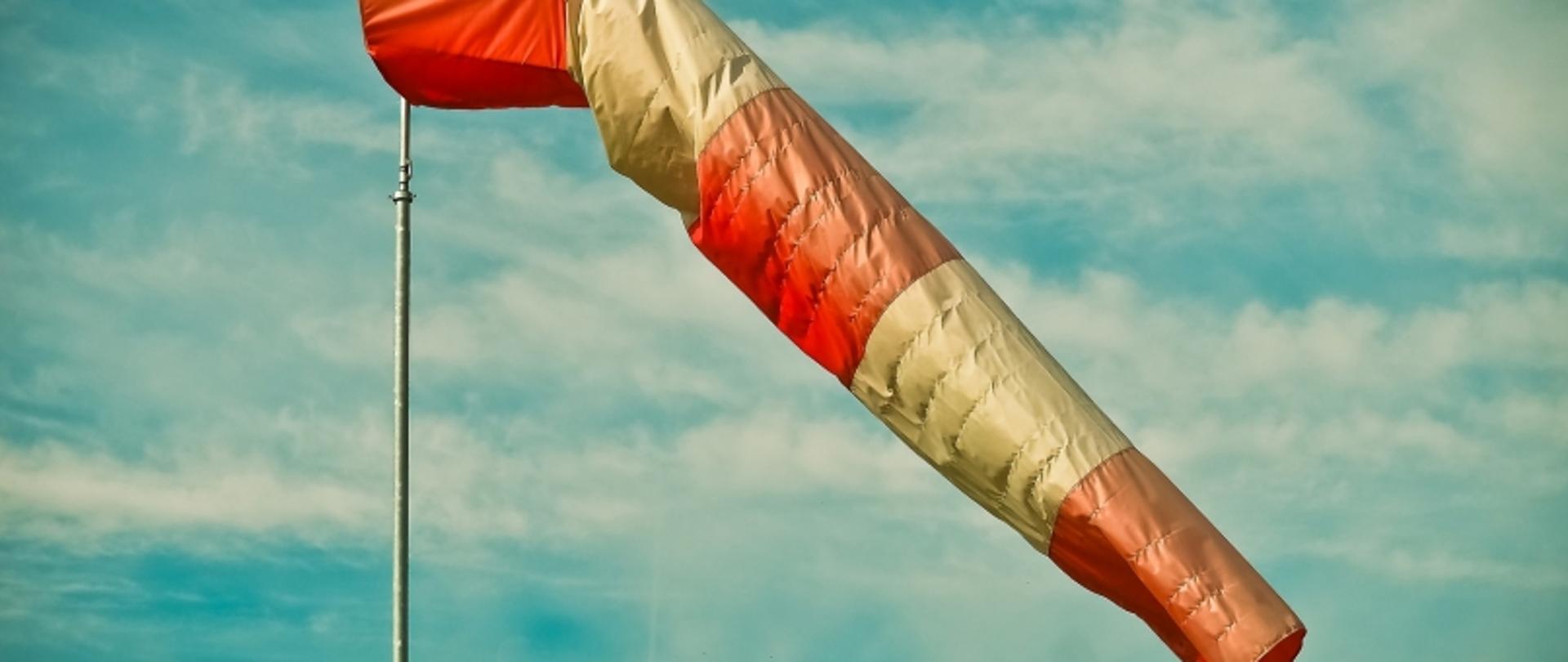 Biało-czerwony rękaw lotniczy na tle zachmurzonego nieba.