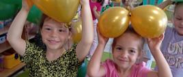 Dzieci pozują do zdjęcia w sali wśród balonów