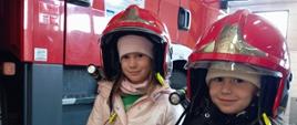 Dzieci pozują do zdjęcia w kasku strażackim