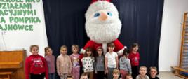 Dzieci pozują do zdjęcia na tle dmuchanego Świętego Mikołaja