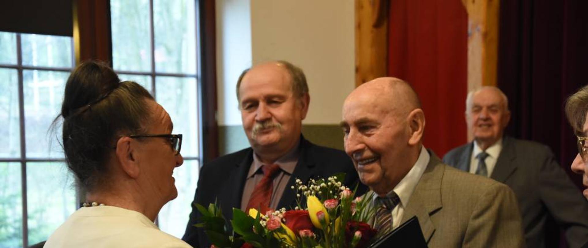 Wręczanie kwiatów Panu Adamowi Pęksie w tle Wójt Gminy Raba Wyżna