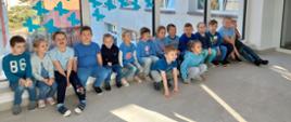 Dzieci pozują do zdjęcia na tle szyby ozdobionej niebieskimi motylami