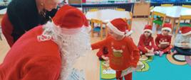 Mikołajki w przedszkolu - Mikołaj rozdaje dzieciom prezenty