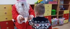 Człowiek przebrany za świętego Mikołaja wręcza dzieciom prezenty