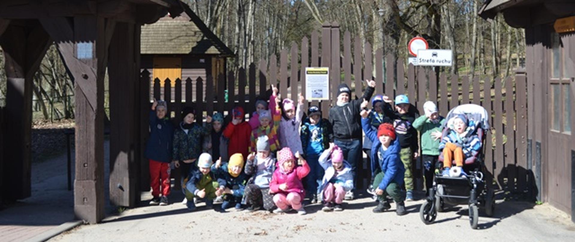 Dzieci pozują do zdjęcia przed bramą do Białowieskiego Parku Narodowego