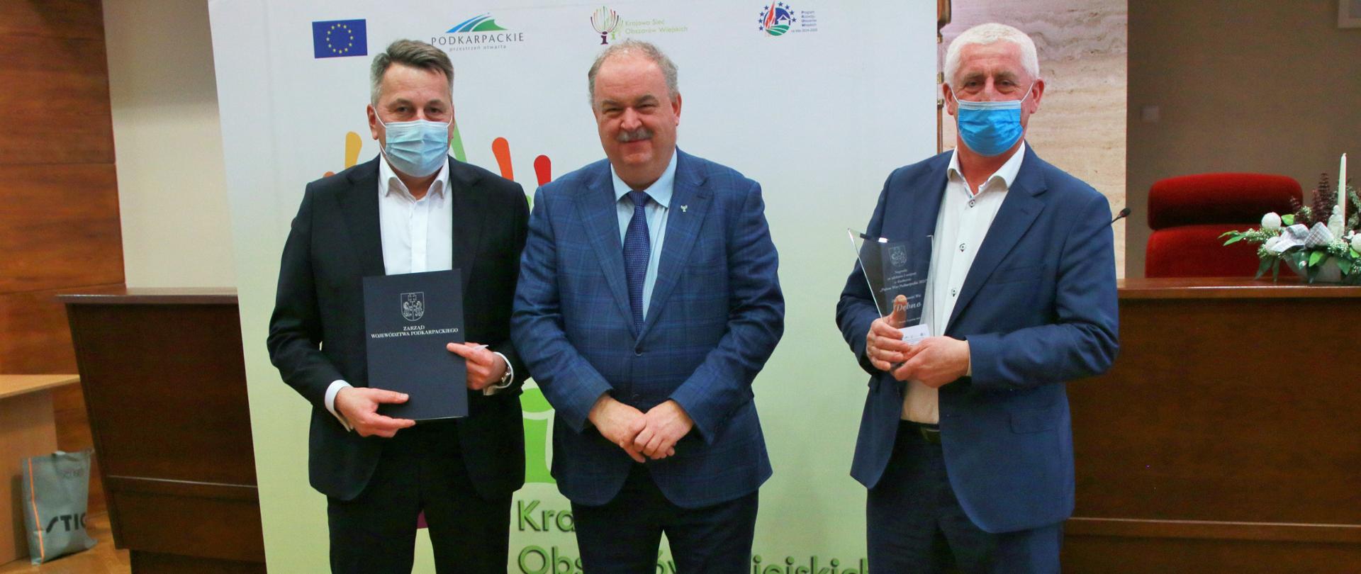 Na zdjęciu stoją trzej mężczyźni pozujący do zdjęcia z wręczonymi nagrodami.