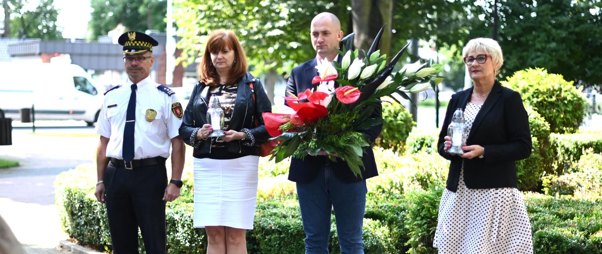 Cztery osoby stoją przed pomnikiem.