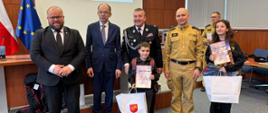 Spotkanie nagrodzonych w kategorii I w Starostwie. Na zdjęciu nagrodzona dwójka dzieci z upominkami oraz dyplomem, przedstawiciele OSP oraz Starosta Powiatu Nowotarskiego i Burmistrz Nowego Targu