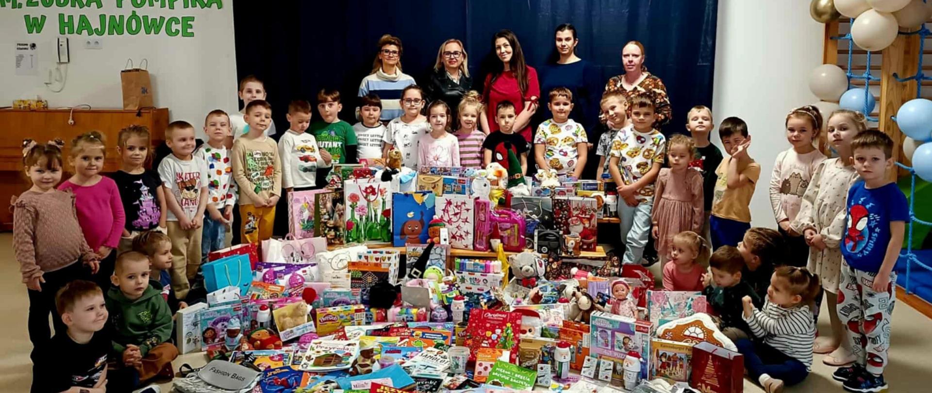 Dzieci, dyrekcja i nauczycielki pozują do zdjęcia wraz z zebranymi przedmiotami