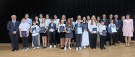 Uczniowie ze szkoły w Skawie nr 3 wspólnie zp. dyrektorem, panem wójtem, zastępcą wójta, panią Ewą Miśkowiec oraz pracownikiem ZEAS. Wszyscy pozują do zdjęcia na scenie w remizie OSP.