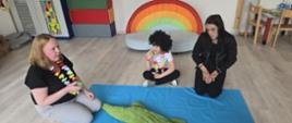 W trakcie zajęć - rodzice z dziećmi siedzą przed niebieską matą, na której leży krokodyl