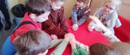 Gry edukacyjne - dzieci siedzą przy stole, trzymają się za ręce