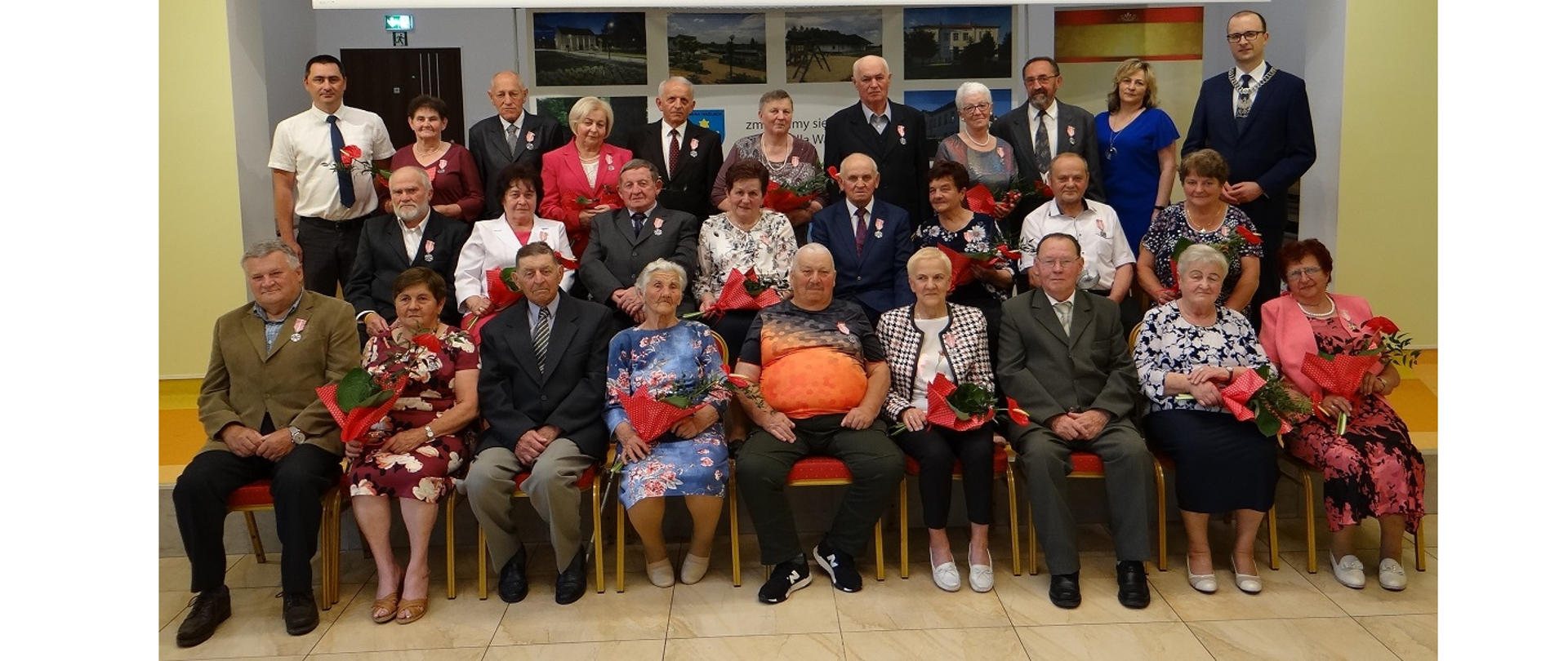 Wspólna fotografia uczestników spotkania. Zebrani siedzą na krzesłach w dwóch rzędach. Trzeci rząd stoi z tyłu. 