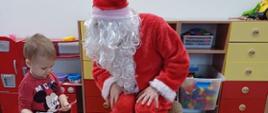 Człowiek przebrany za świętego Mikołaja wręcza dzieciom prezenty