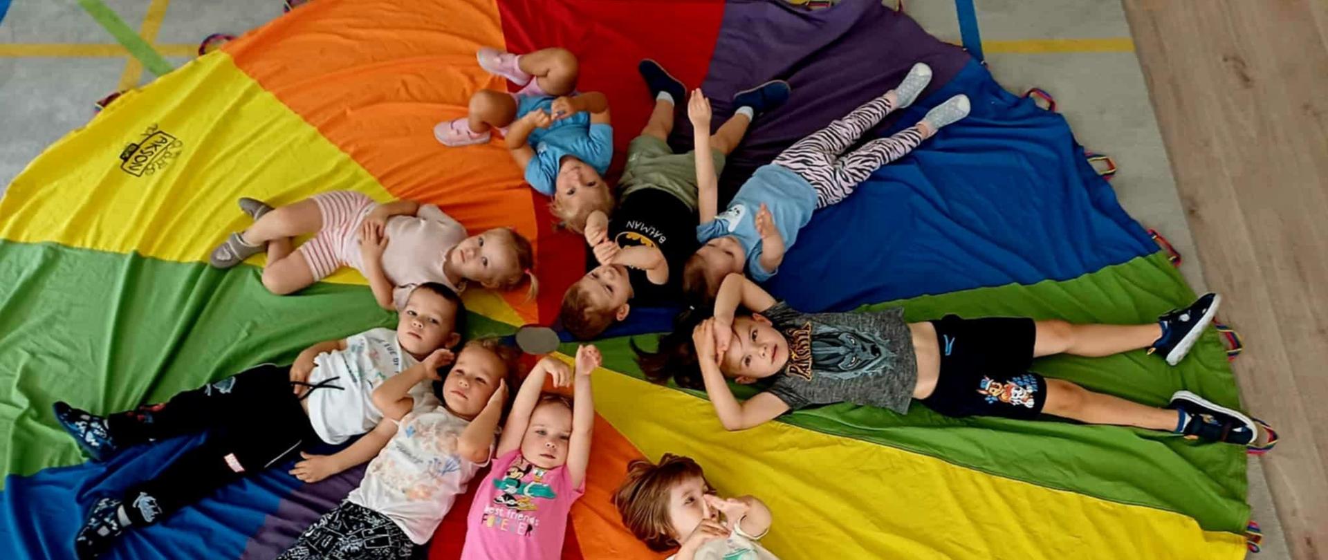 Zabawy w grupie 3latków - dzieci leżą na kolorowej płachcie, pozują do zdjęcia