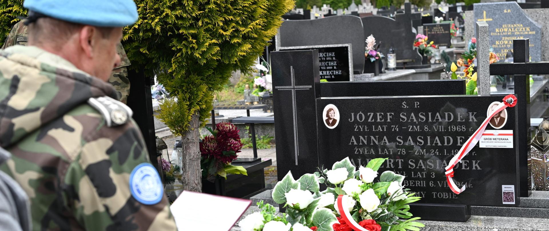 Żołnierz składa wiązankę na nagrobku.